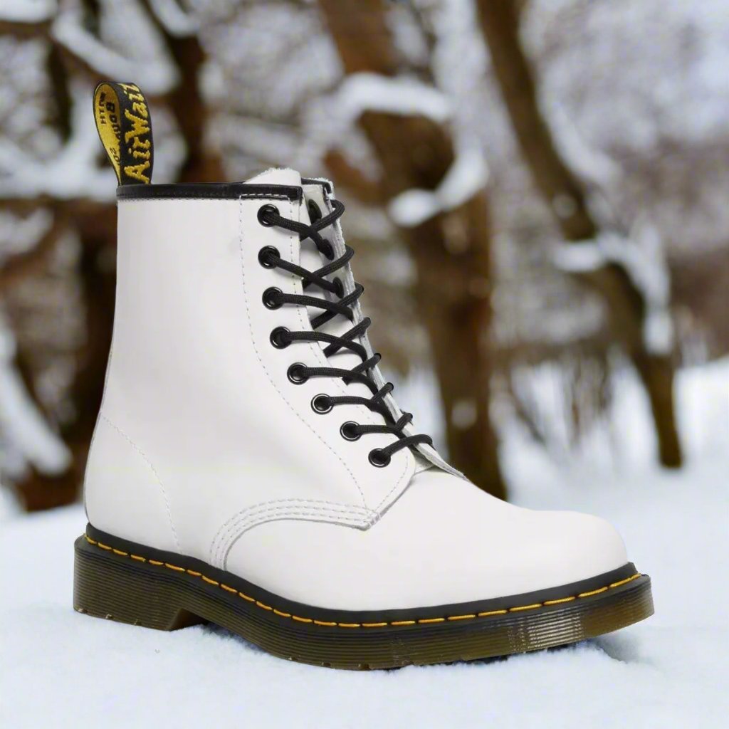 Witte hoge dameslaarzen met veters in de sneeuw