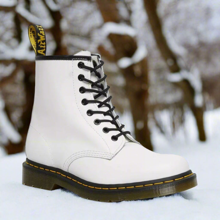 Witte hoge dameslaarzen met veters in de sneeuw