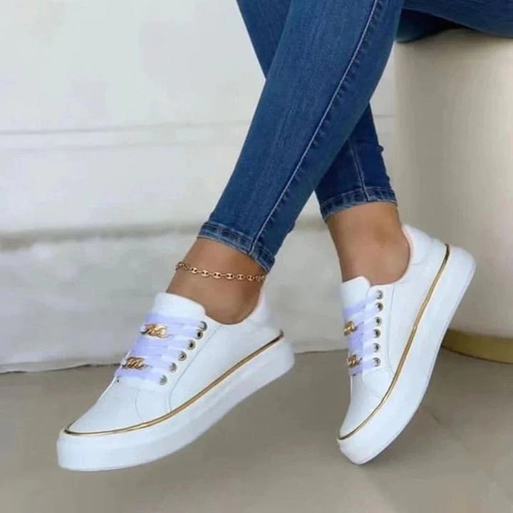 "Stijlvolle dames sneakers met gouden accenten, wit en zwart ontwerp. Chique en comfortabel voor elke gelegenheid."