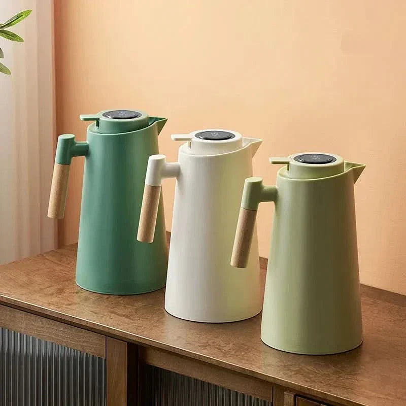 Drie verschillende kleuren thermoskannen op een houten ondergrond
