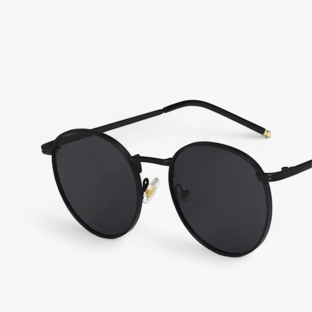 Detailopname van uniseks zonnebril 'Nova' met ronde glazen, toont het hoogwaardige metalen frame en trendy design.