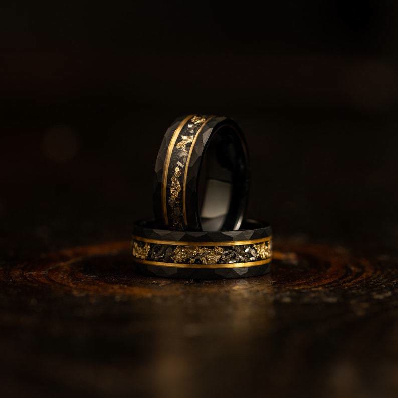 Wolfram ring met gouden blad en zwarte meteoriet inlay, gedragen aan vinger, luxe & robuuste uitstraling.