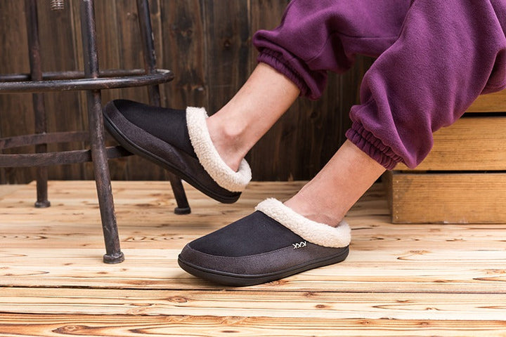 Man draagt comfortabele warme heren winterpantoffels Lars, genietend van voetcomfort binnenshuis.