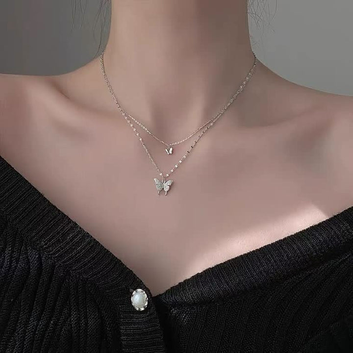 Model draagt de elegante zilverkleurige vlinder halsketting, een chique accessoire.