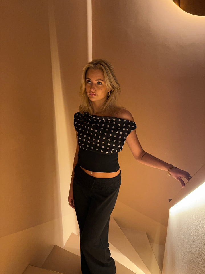 "Zwart-witte polkadot dames top met verstelbare striksluiting voor elegante pasvorm, luchtige stof en vintage flair."