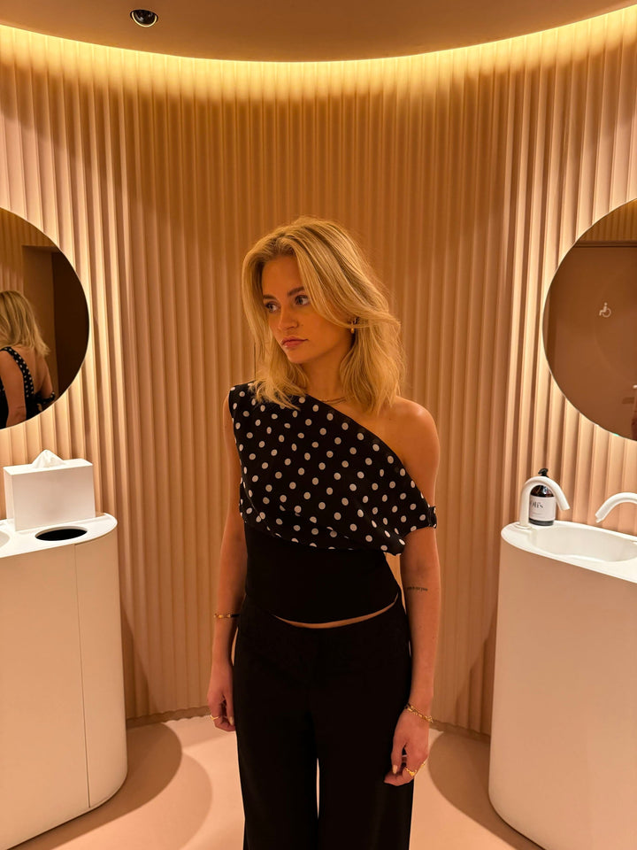 "Zwart-witte polkadot dames top met verstelbare striksluiting voor elegante pasvorm, luchtige stof en vintage flair."