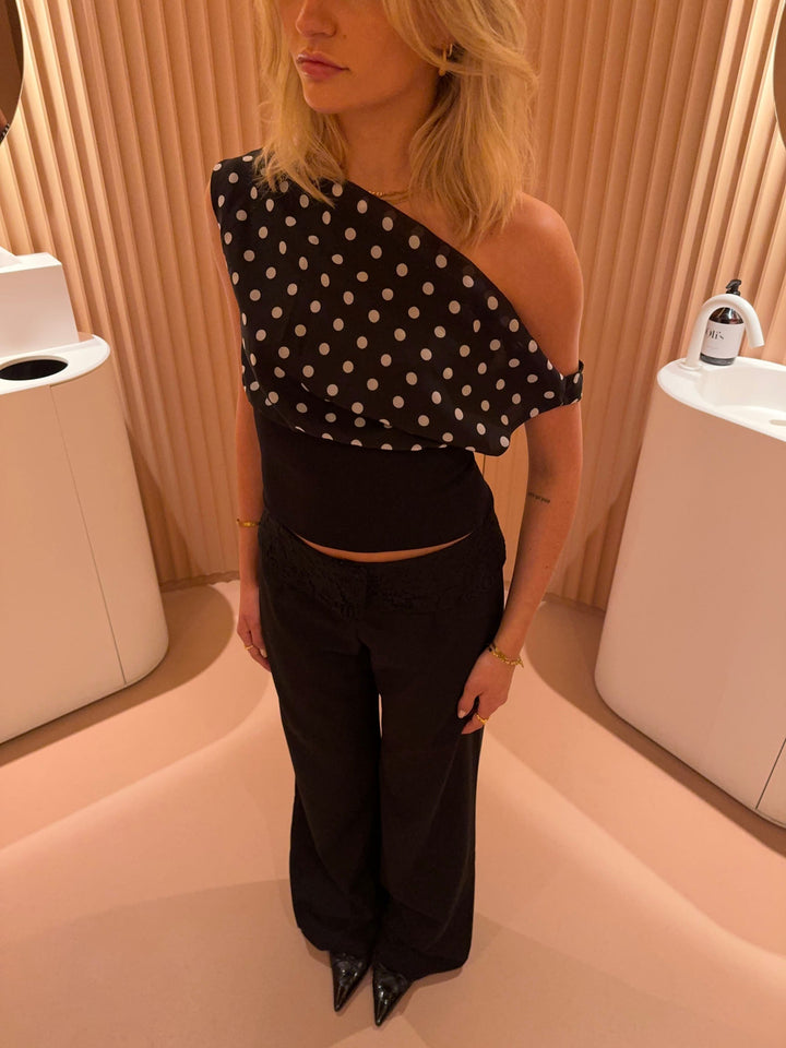 "Zwart-witte polkadot dames top met verstelbare striksluiting voor elegante pasvorm, luchtige stof en vintage flair."