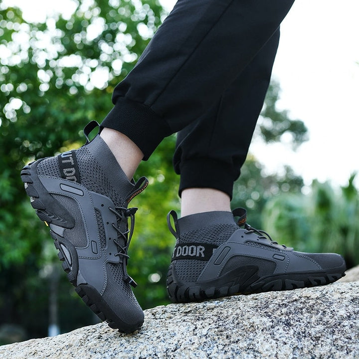 Heren barefootschoenen aan voeten, staand op een natuurlijke ondergrond, voor een authentieke blotevoetensensatie.